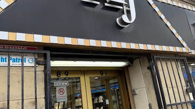Sign for KJ Jewellers with a decorative black and gold facade, featuring a glass entrance and security bars.
