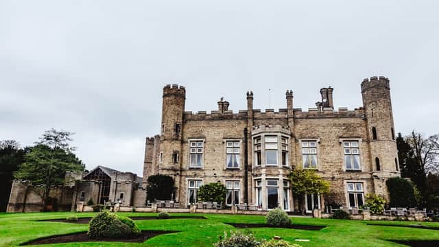 Historic stone castle with turrets, manicured lawns, and lush greenery in South Cave, Yorkshire.