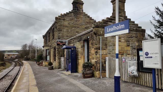 Stone building with a slate roof, sign reading "Lealholm," and a train platform beside railway tracks.