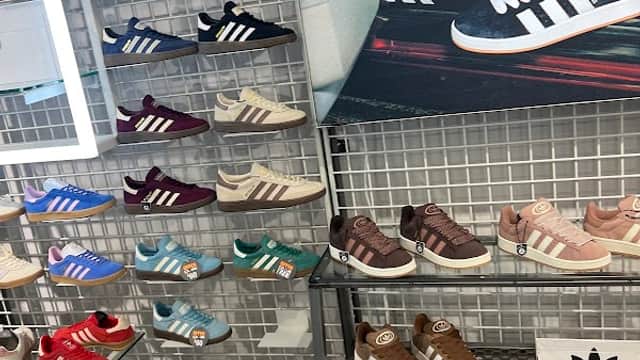 Colorful display of various Adidas sneakers on racks, showcasing different styles and colors in a retail setting.