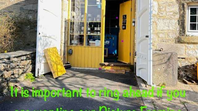 Entrance to The Little Gallery and Framing Studio with yellow doors, stone walls, and a sign about calling ahead.