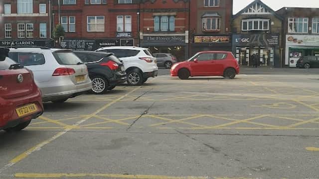 Pay & Display car park with parked cars and brick buildings in South Elmsall, Yorkshire.