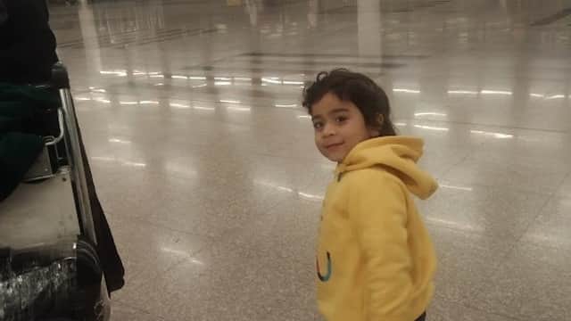 A child in a yellow hoodie walks through a spacious, well-lit car park with polished floors.
