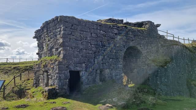 Historic stone structure of Toft Gate Lime Kiln with grassy surroundings and blue sky in Bewerley, Yorkshire.