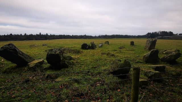 Ancient stone circle surrounded by grassy fields and trees under a cloudy sky in Harwood Dale, Yorkshire.