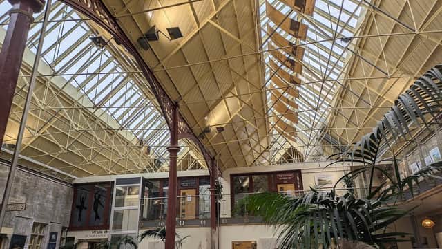 High ceiling with metal beams, large windows, and indoor plants in a spacious recreational area.