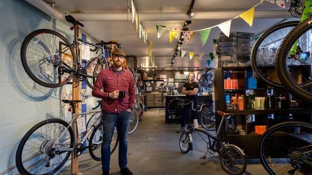 Interior of Russell's Bicycle Shed with bikes on display, a man holding a mug, and colorful bunting overhead.