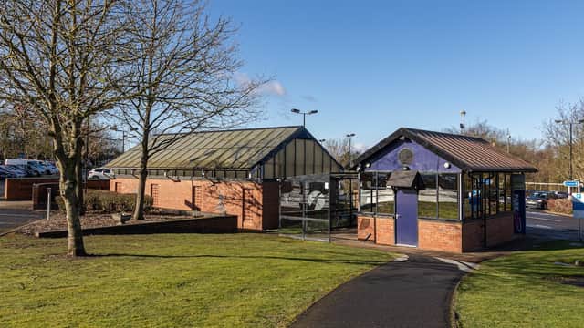 Grimston Bar Park & Ride with a modern shelter, grassy area, and parked cars under a clear blue sky.