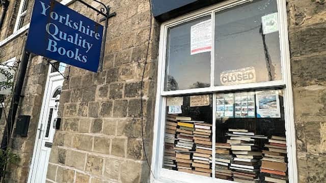 Sign for "Yorkshire Quality Books" above a closed window displaying stacked books in a stone building.