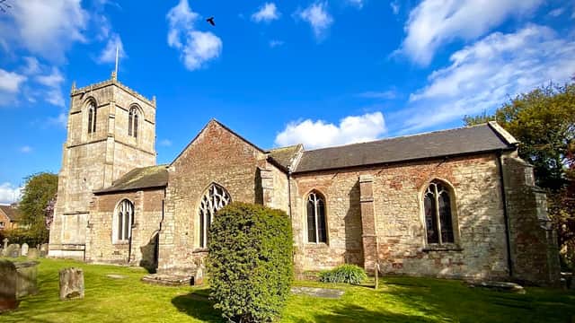 All Hallows Church features a stone exterior, a tall tower, arched windows, and a lush green graveyard.