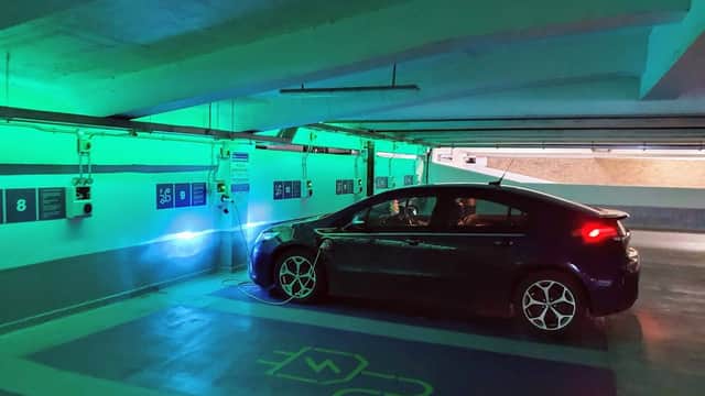 Multi-storey car park featuring a parked car under green lighting, with numbered parking spaces visible on the walls.