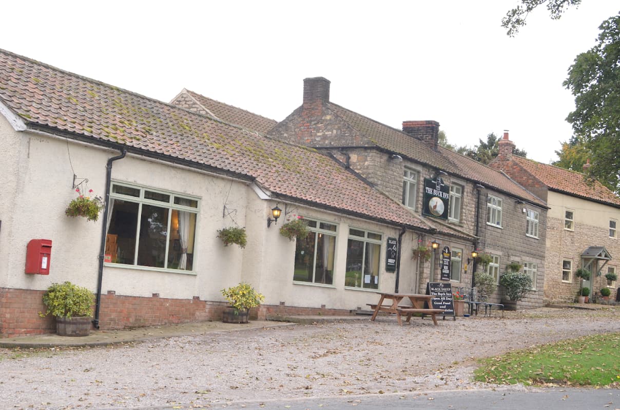 Charming Bed & Breakfast with stone and brick exterior, outdoor seating, and flower baskets in a quaint Yorkshire village.