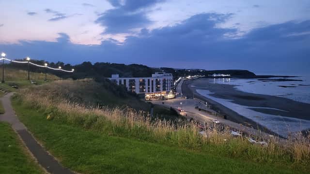 North Street Car Park overlooks a beach at dusk, with lights along the path and buildings in the background.