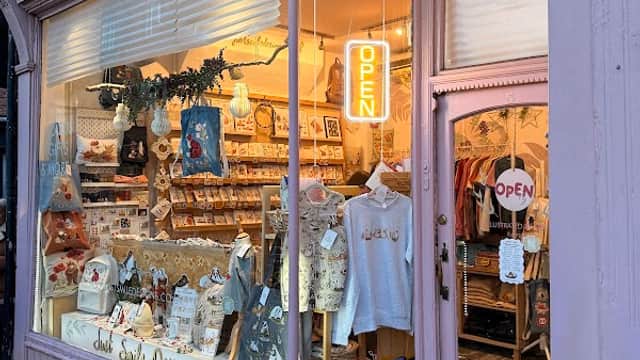 Brightly lit gift shop window featuring various items, including clothing and accessories, with an "OPEN" sign.