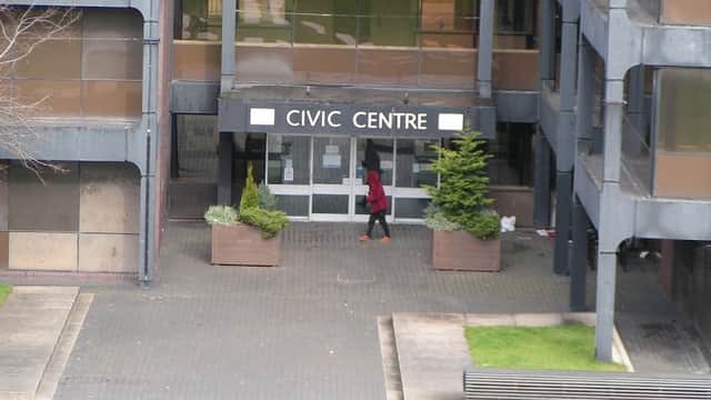 Civic Centre entrance with glass doors, planters, and a person walking by on a paved pathway.