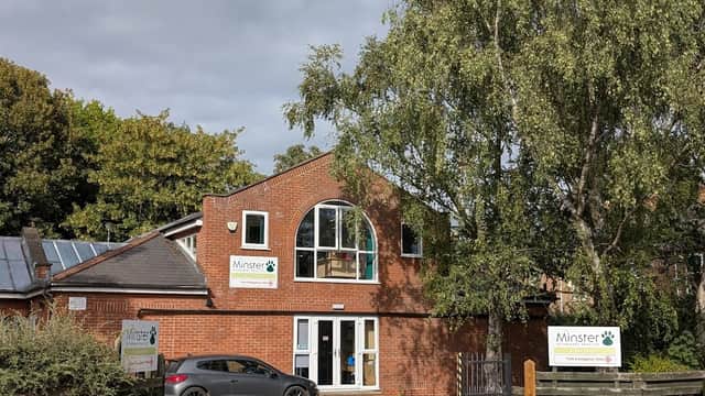 Minster Veterinary Practice building with large windows, greenery, and signage on a cloudy day.