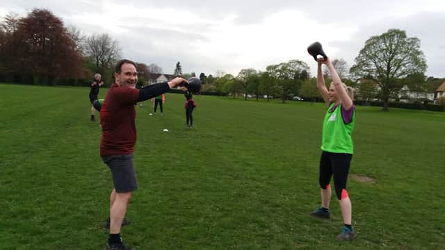 Participants engaged in outdoor fitness training at Army Fit Addingham Bootcamp, with kettlebells and cones on the grass.