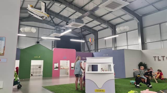 Indoor play area with colorful walls, children playing, and a model airplane suspended from the ceiling.