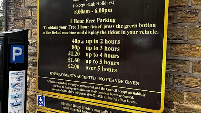 Sign for Royd Lane Car Park with parking charges, hours, and conditions displayed on a yellow and black background.