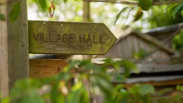 Wooden sign pointing to "Village Hall" surrounded by greenery in Westerdale, Yorkshire.