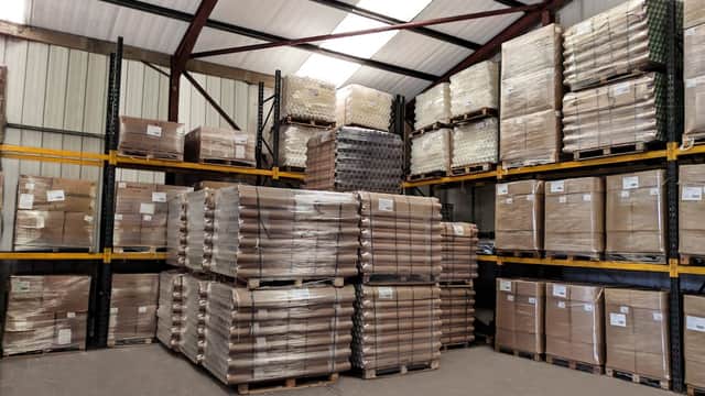 Warehouse interior with stacked pallets of packaged paper tubes and shelves filled with boxes in Cliffe Common, Yorkshire.