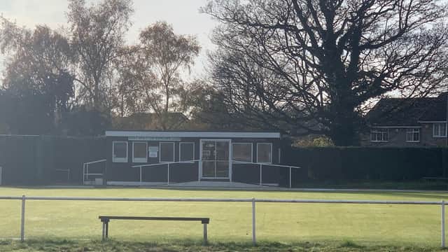West Bretton Bowling Club building with large windows, surrounded by green lawn and trees, under a cloudy sky.