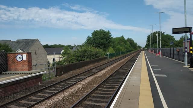 Micklefield Station platform with railway tracks, trees in the background, and clear blue sky.