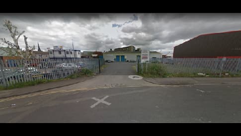 Pay & Display parking area entrance in Rotherham, surrounded by a metal fence and industrial buildings under cloudy skies.