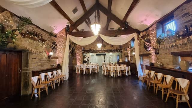 Elegant event space with wooden beams, draped fabric, and decorated tables, creating a warm, inviting atmosphere.