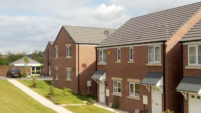 Modern brick houses with neatly trimmed lawns and a cloudy sky in Highfield Park, Wombwell, Yorkshire.