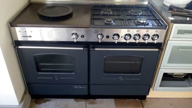 Dual oven range with gas burners, stainless steel finish, and black accents, set in a modern kitchen environment.