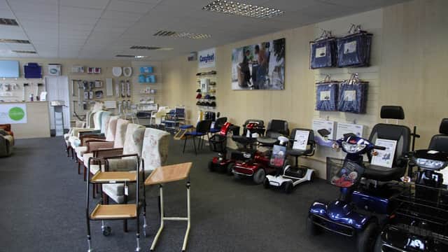 Showroom interior with mobility scooters, chairs, and mobility aids displayed on shelves and walls.