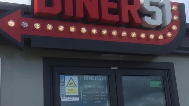 Brightly lit sign reading "DINER 51" with retro-style lights, featuring a window displaying opening times and a "CCTV in operation" notice.