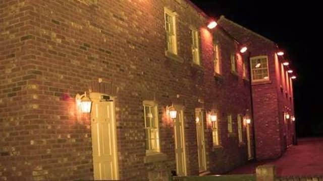 Brick building with multiple doors and warm lighting, set against a dark night sky in East Cowick, Yorkshire.