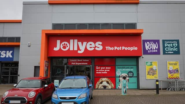Bright storefront of Jollyes - The Pet People, featuring colorful signage and parked cars in front.