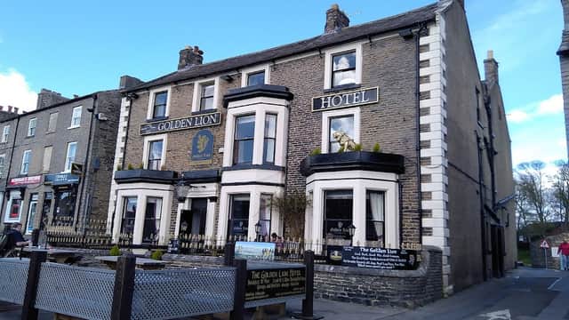 Historic stone building with "Golden Lion Hotel" signage, featuring a lion statue and outdoor seating area.