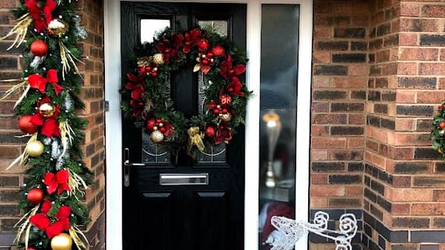 Festive entrance with a decorated door, wreath, garland, red bows, and a glowing reindeer figure.