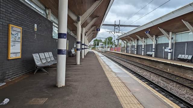 Platform at Rotherham Central station with benches, track, and overhead railway structures under a cloudy sky.