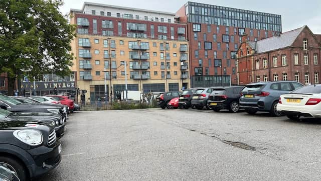 Carver Lane Car Park with parked cars, modern buildings, and a historic brick structure in Sheffield.