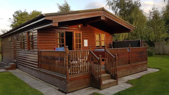 Wooden holiday lodge with a porch, surrounded by greenery and a clear sky in Sutton upon Derwent, Yorkshire.