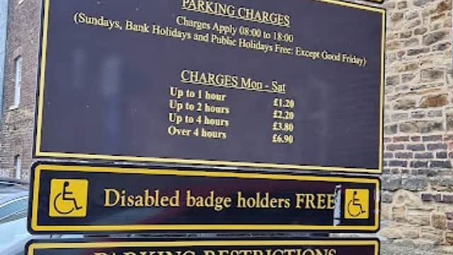 Welcome sign for Carter Street Car Park, detailing parking charges and restrictions, with a brick building in the background.