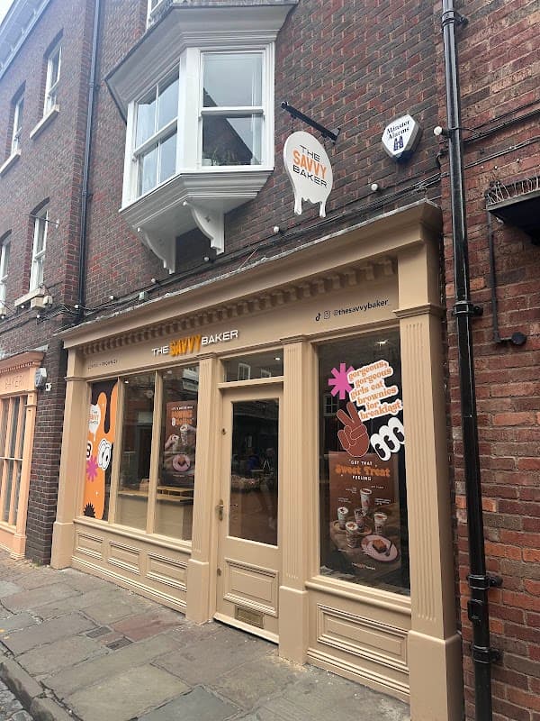 Charming cafe exterior with large windows, orange signage, and decorative elements in a historic York street.