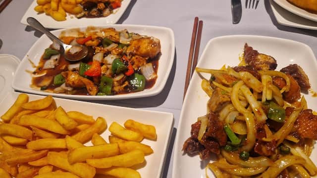Two plates of Cantonese dishes with chicken and vegetables, accompanied by a serving of golden fries.