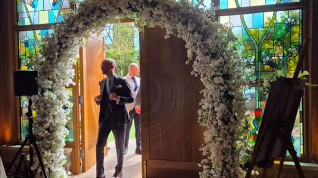 Elegant floral archway at The Petal Studio entrance, with stained glass windows and a stylish interior.