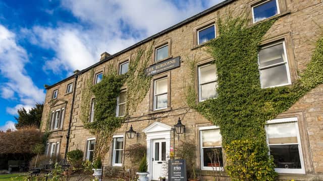Historic stone building with ivy-covered walls, large windows, and a welcoming entrance in Reeth, Yorkshire.