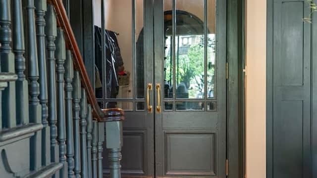 Elegant entrance with double doors, a pendant light, and a wooden staircase leading to a herringbone floor.