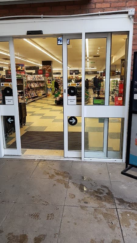 Entrance to Co-op Food with shopping aisles visible, shoppers inside, and signage on glass doors.