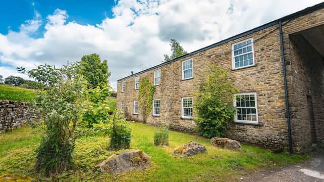 Stone building with large windows, surrounded by greenery and a blue sky with clouds in Simonstone, North Yorkshire.