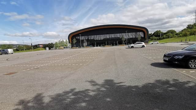 Spacious car park at Sheffield Olympic Legacy Park, featuring a modern building and clear blue skies.