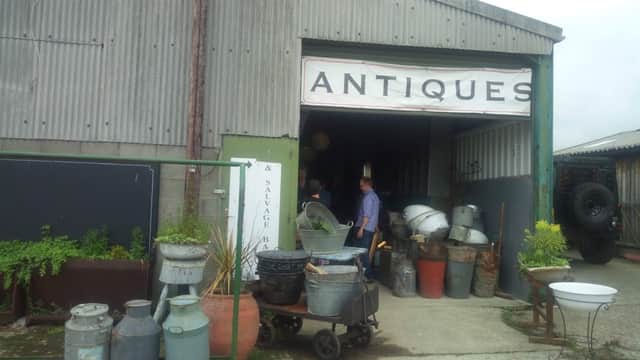 Entrance to Castleforge Antiques Ltd with various vintage items and planters outside, set in a rustic building.